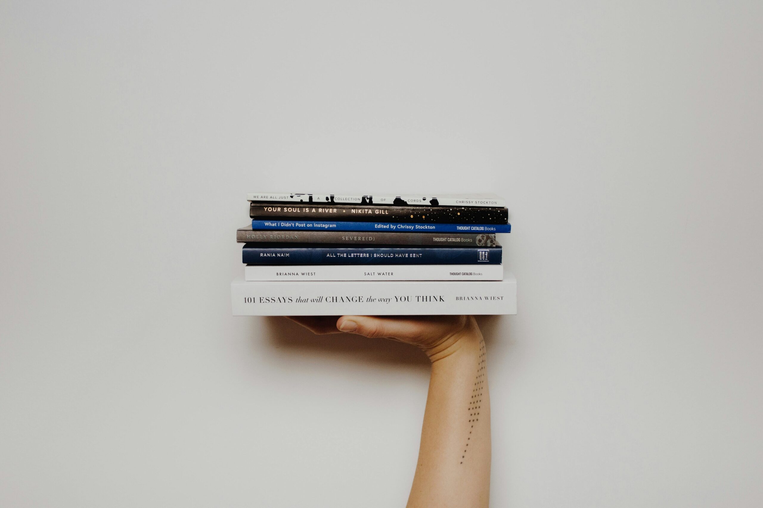 Hand holding a stack of books against a minimal white background, perfect for educational themes.