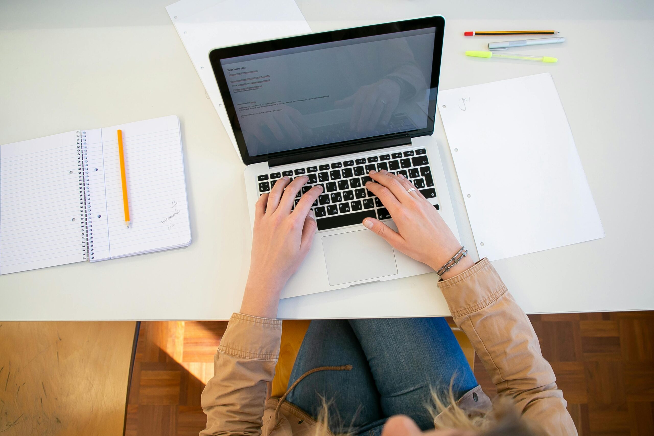 Overhead view of student typing on laptop surrounded by notes.